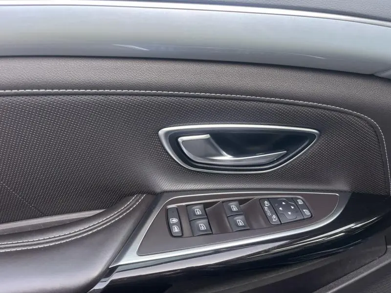 Gros plan sur la porte intérieure côté gauche du Renault Espace gris Cassiopée, avec commandes des vitres et poignée argentée.