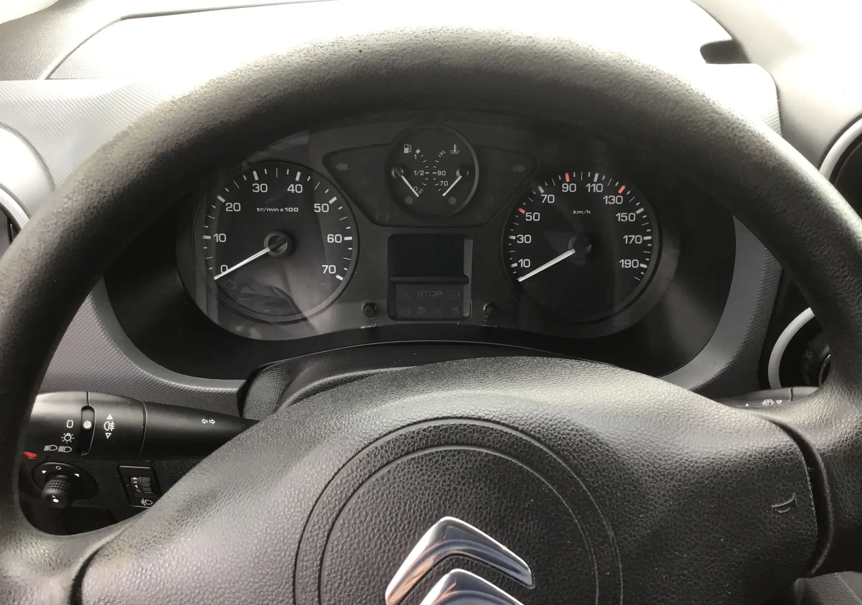 Vue rapprochée du tableau de bord et volant noir avec logo Citroën d'un Berlingo blanc diesel de 2019.