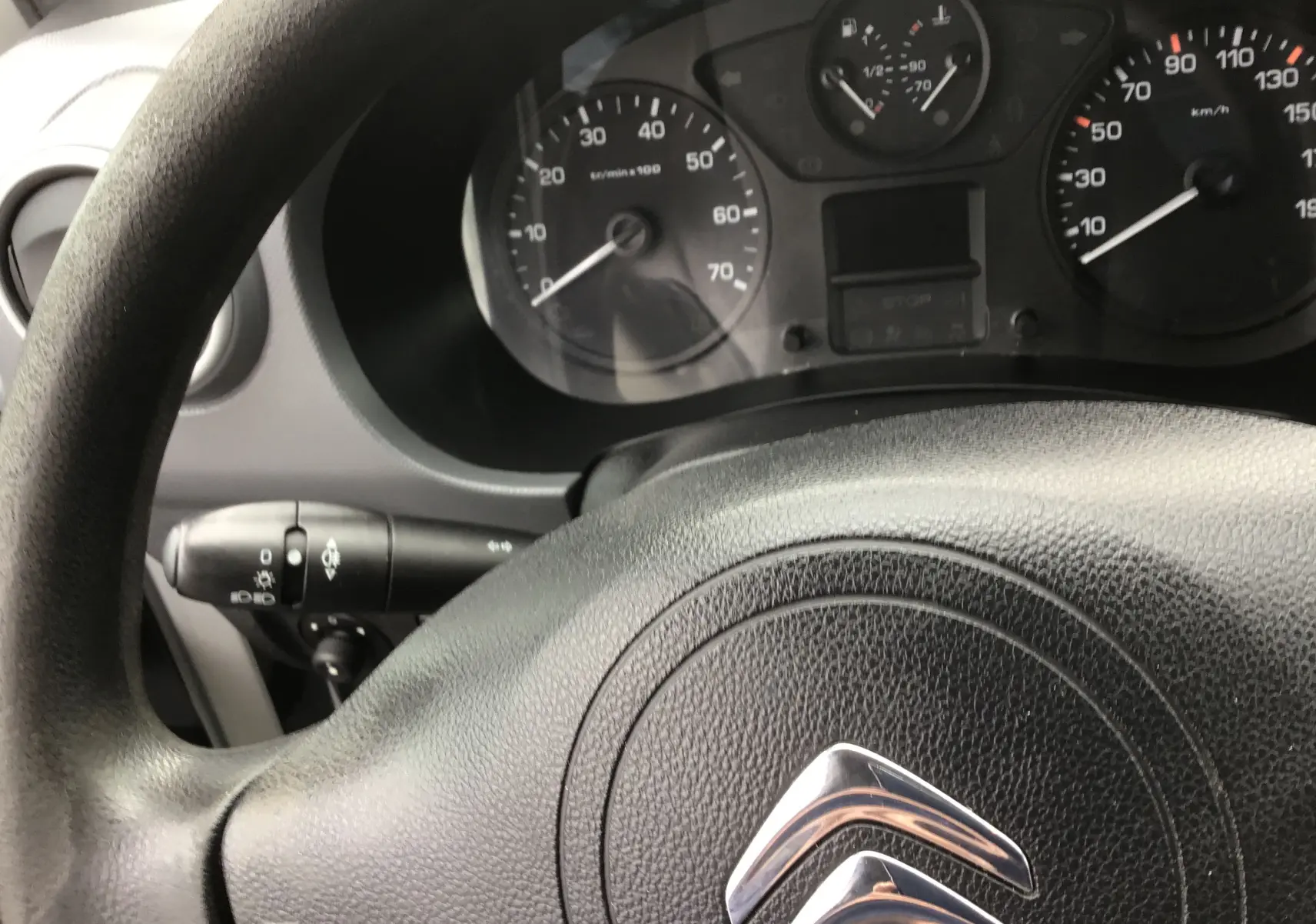 Vue rapprochée du volant noir et du tableau de bord du Citroën Berlingo blanc, version 2019 diesel.