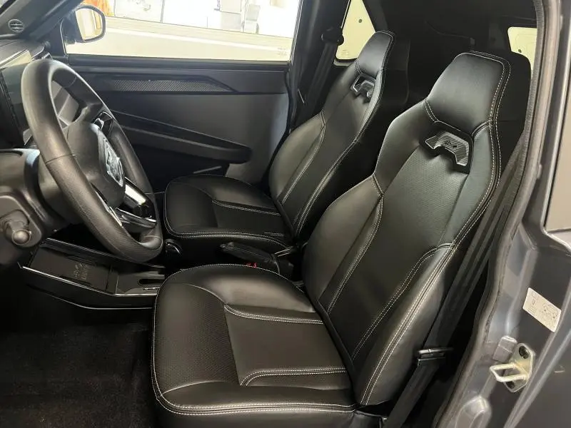 Vue intérieure côté conducteur du Ligier JS50 Sport Elite E5+ 2025 gris, sièges sport noirs avec surpiqûres blanches.