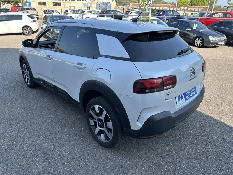 Vue 3/4 arrière droite d'une Citroën C4 Cactus blanche 2018 avec toit noir et jantes distinctives bicolores.