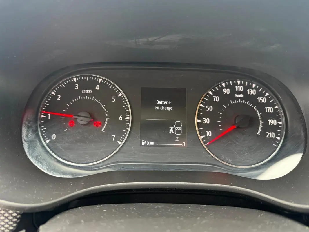 Vue rapprochée du tableau de bord de la Dacia Sandero blanc, affichant le compte-tours, la vitesse et un message "Batterie en charge".