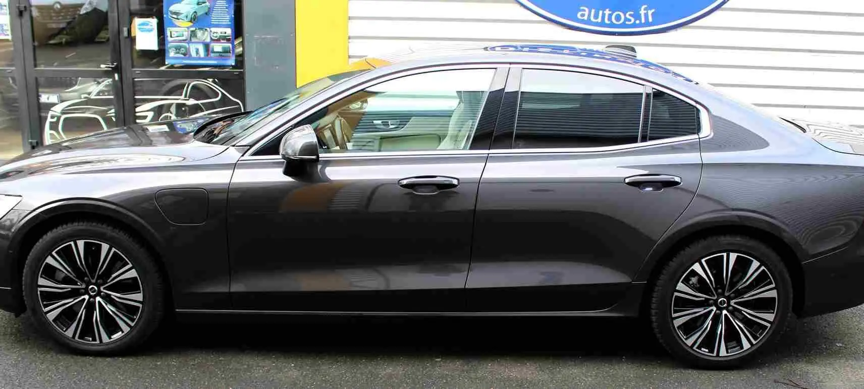 Profil côté gauche d'une Volvo S60 hybride rechargeable gris métal 2024 avec jantes alliage distinctives et lignes épurées.