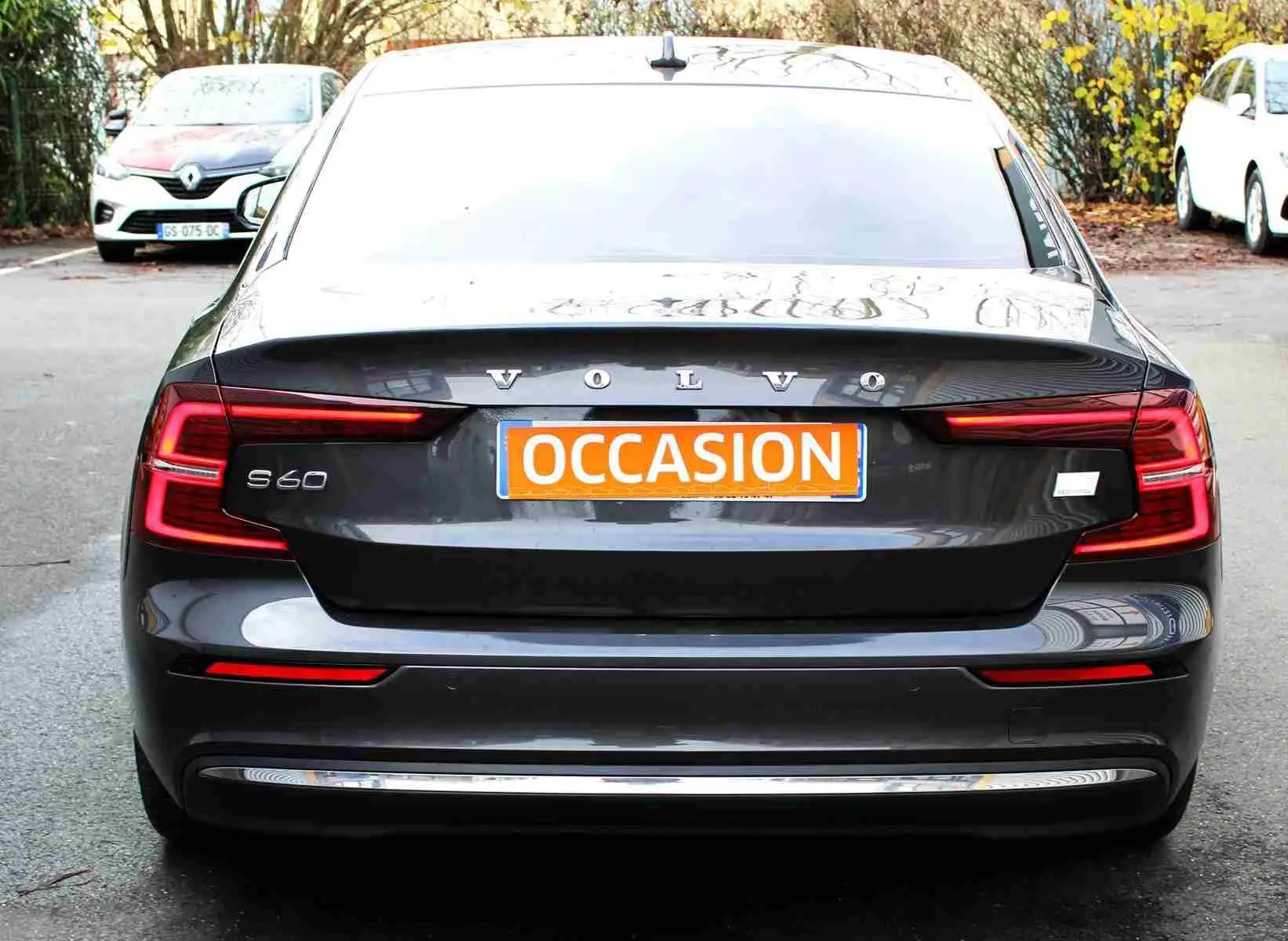 Vue arrière d'une Volvo S60 gris métal 2024 avec feux LED en forme de C et plaque "OCCASION" orange.