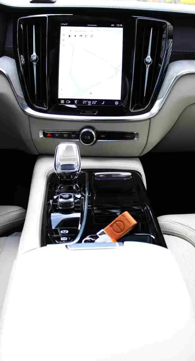 Vue rapprochée de la console centrale intérieure du Volvo S60 2024 avec écran tactile, levier de vitesses cristal et clé cuir.