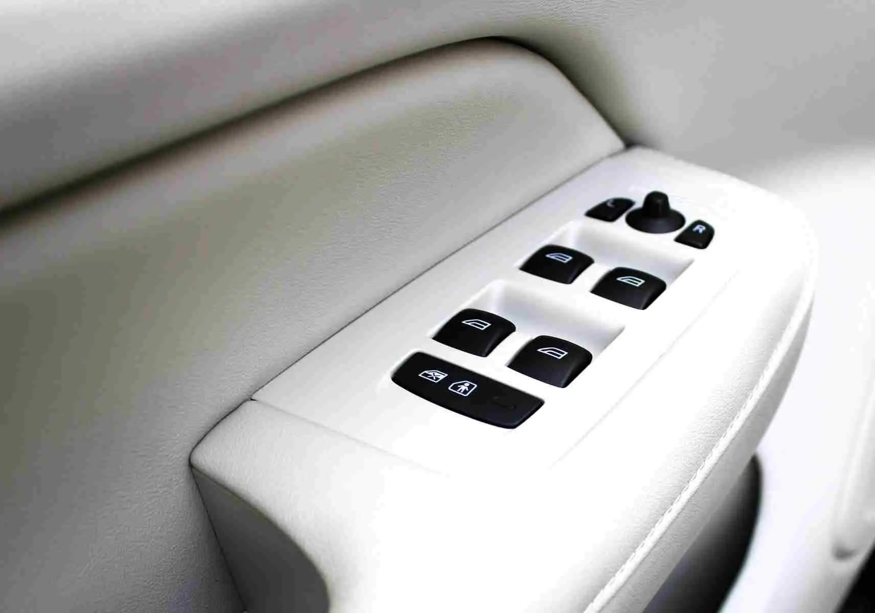 Gros plan sur les commandes des vitres électriques sur la portière intérieure beige du Volvo S60 T6 AWD 2024.