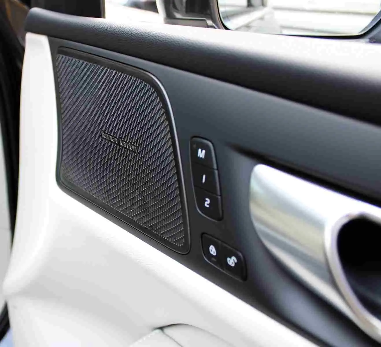 Gros plan sur la porte intérieure côté gauche du Volvo S60 gris métal 2024, avec haut-parleur Harman Kardon et commandes mémoire siège.