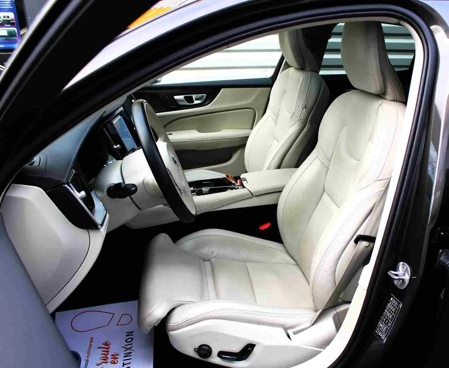 Intérieur clair de la Volvo S60 T6 AWD 2024, vue côté conducteur avec sièges cuir beige et tableau de bord moderne.