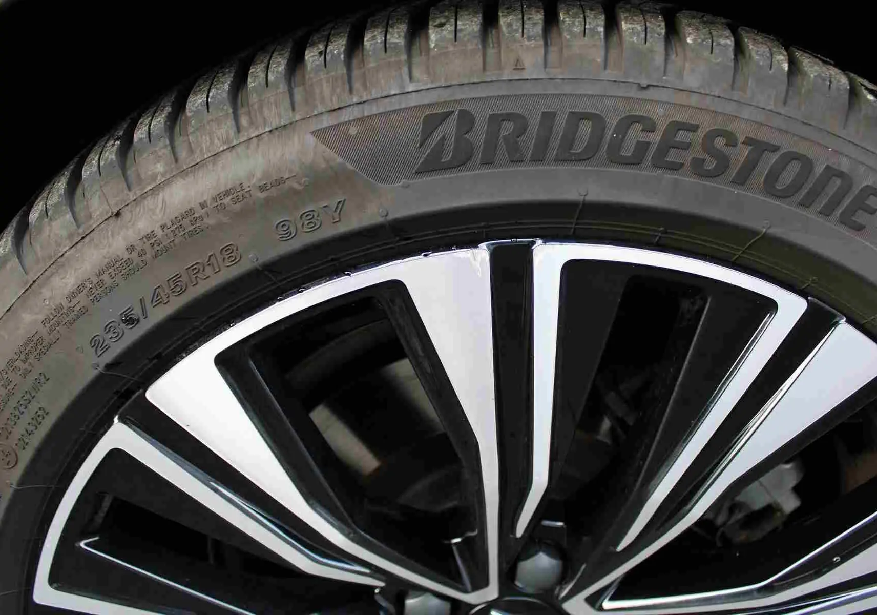 Gros plan sur la jante bicolore noire et chrome d'un pneu Bridgestone du Volvo S60 gris métal 2024 hybride rechargeable.