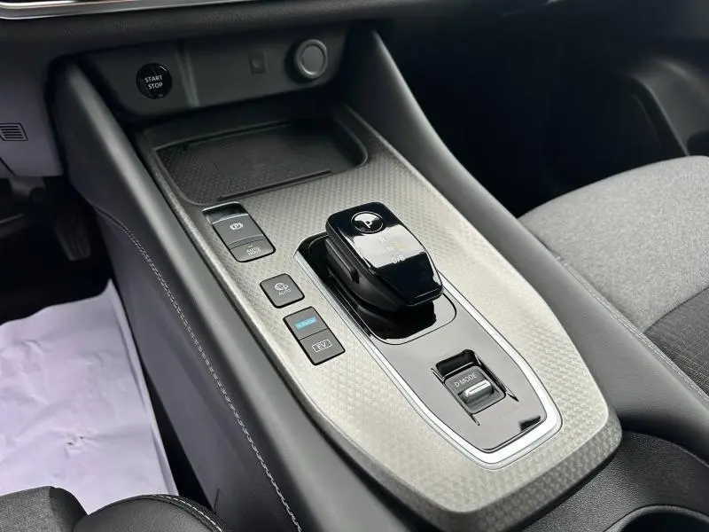 Gros plan sur la console centrale du Nissan Qashqai Hybrid e-POWER 2025, avec levier de vitesse noir et finition gris texturé.