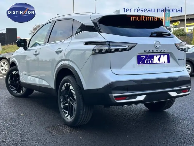Vue 3/4 arrière droite du Nissan Qashqai Hybrid e-POWER blanc nacré avec jantes noires et feux arrière LED distinctifs.