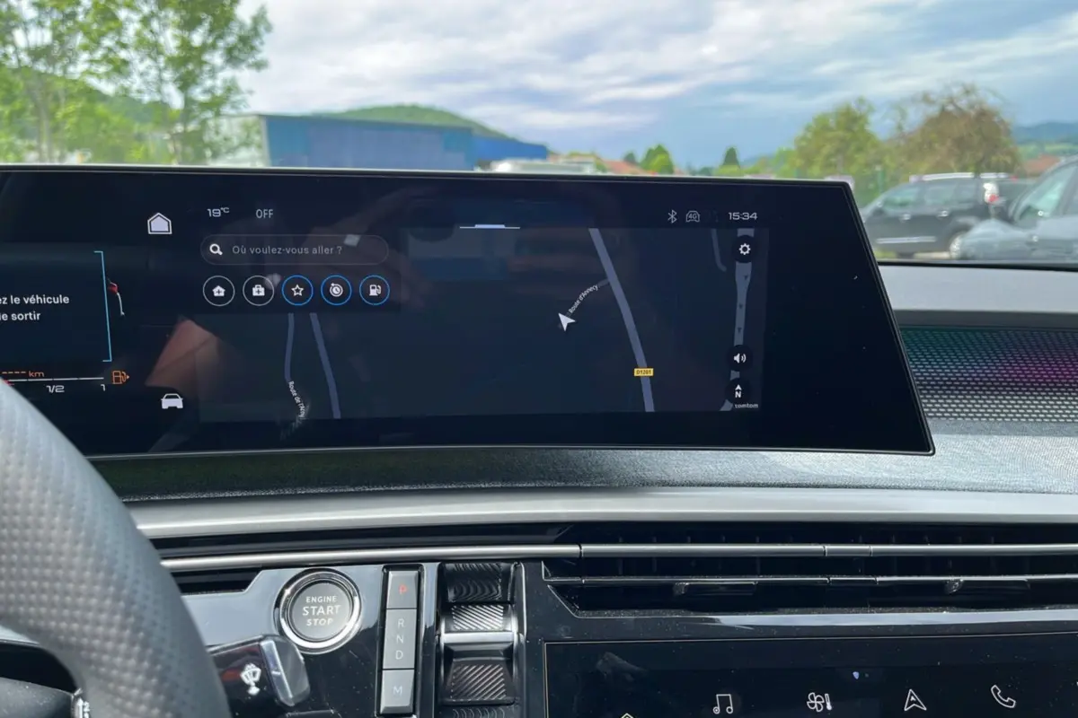 Vue intérieure du tableau de bord du Peugeot 5008 Hybrid 145 GT, écran tactile de navigation et commandes centrales visibles.