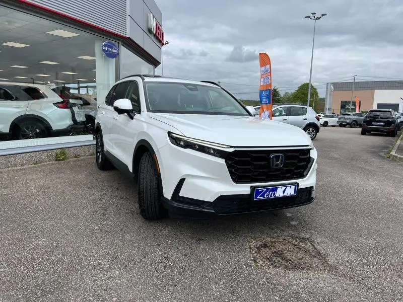 Honda CR-V blanc platine nacré vu de face en léger angle droit, avec calandre noire et feux LED allumés.