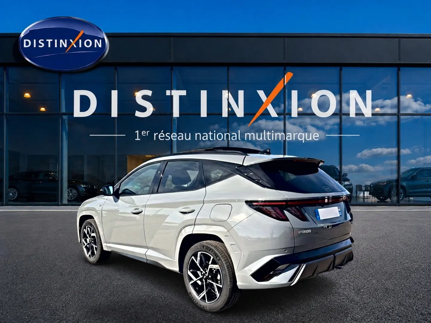 Vue 3/4 arrière droite du Hyundai Tucson gris shadow avec jantes alu noires et toit panoramique noir.
