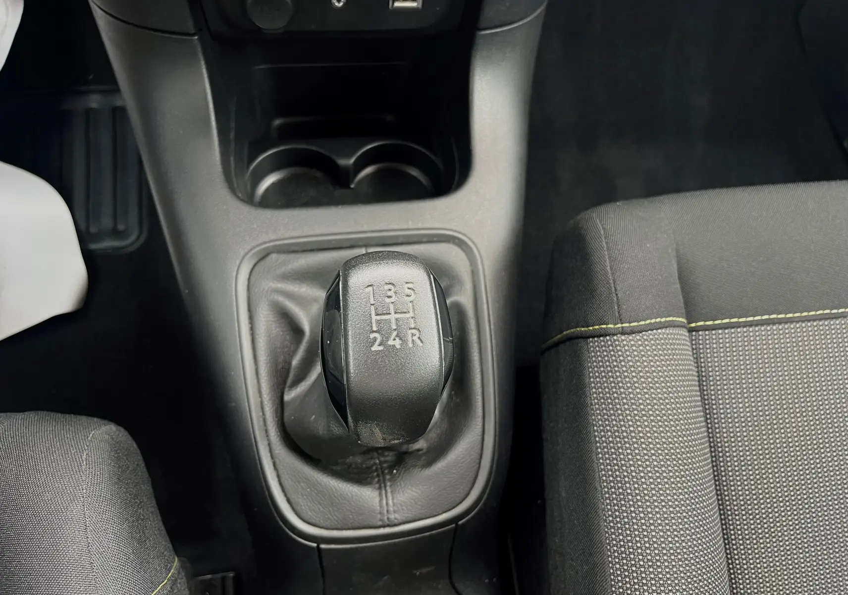 Le levier de vitesses manuel de la Citroën C3 2017 en gros plan, avec siège tissu gris noir visible à droite.