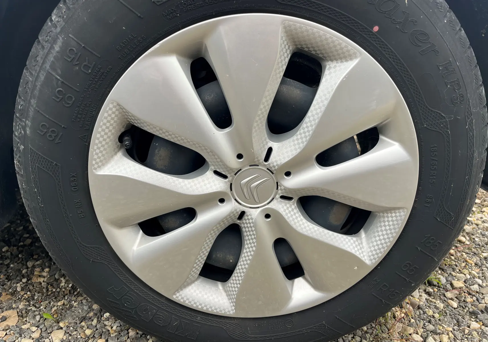 Gros plan sur la jante argentée d'une Citroën C3 blanche, mettant en valeur le logo Citroën au centre.