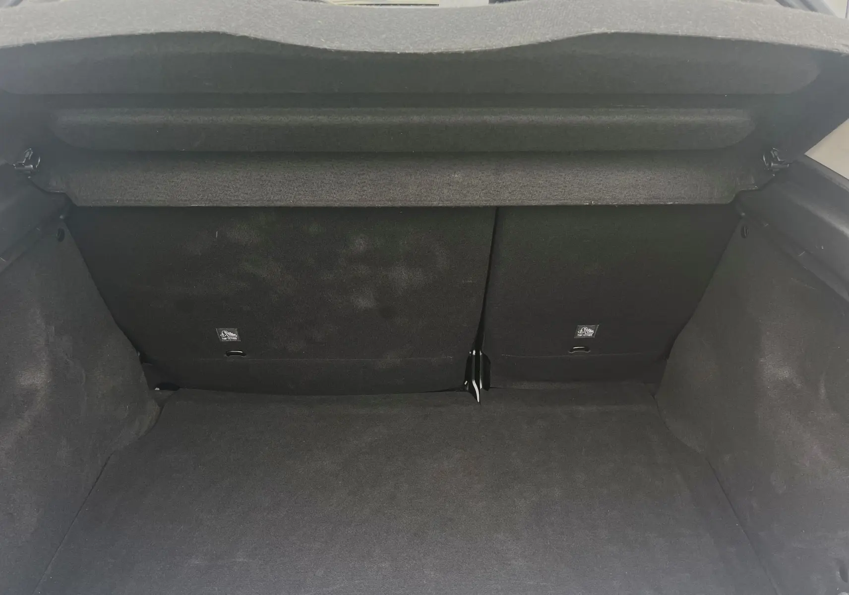 Coffre ouvert de Citroën C3 blanc 2017, vue intérieure arrière montrant la banquette arrière et le tapis de coffre noir.