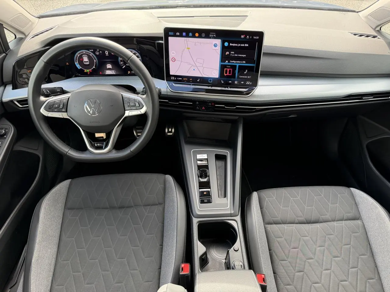 Vue intérieure frontale du poste de conduite de la Volkswagen Golf 2024 avec tableau de bord digital et écran tactile central.