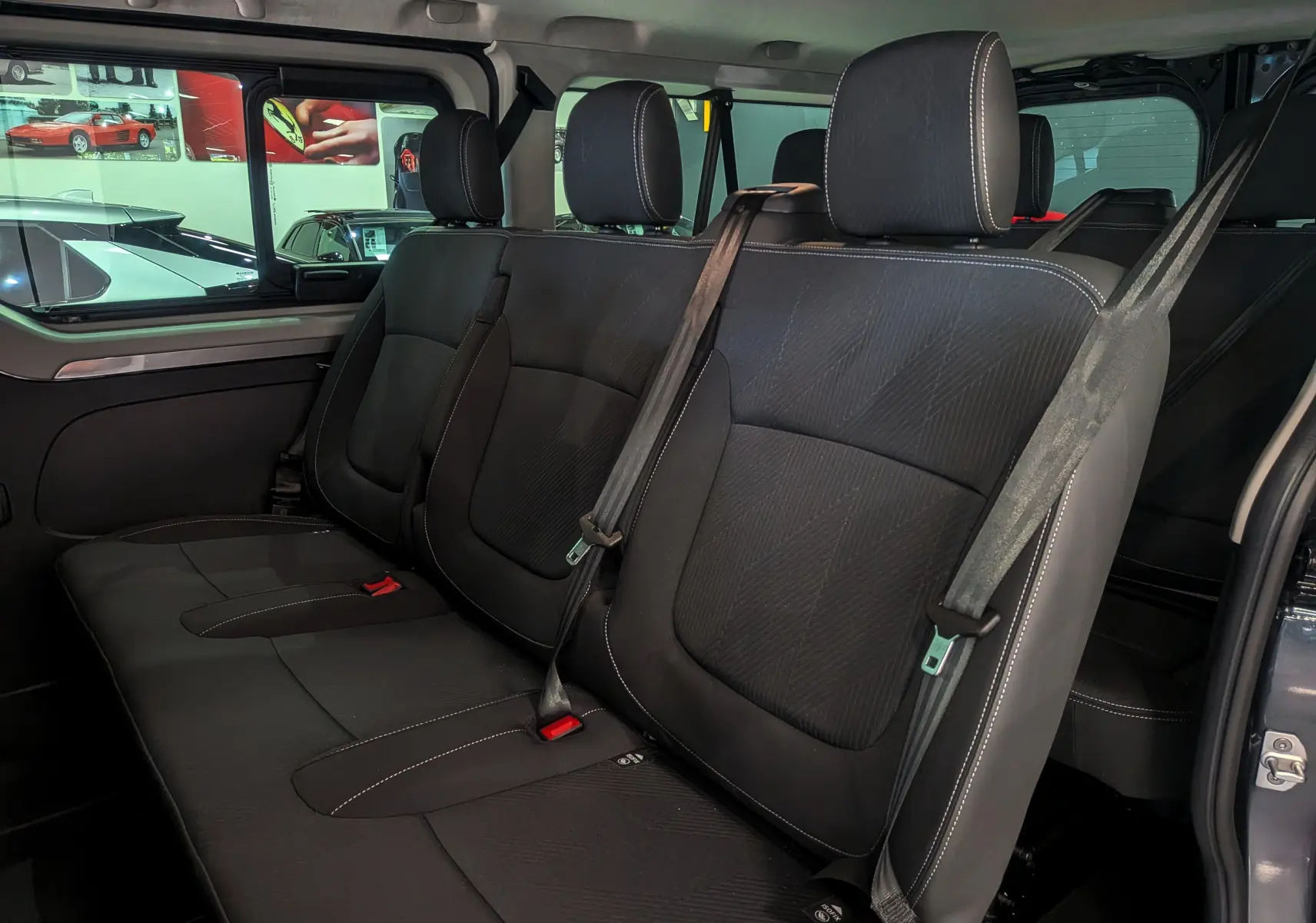 Vue intérieure sur la banquette arrière en tissu noir du Renault Trafic Combi 2025, porte latérale ouverte.