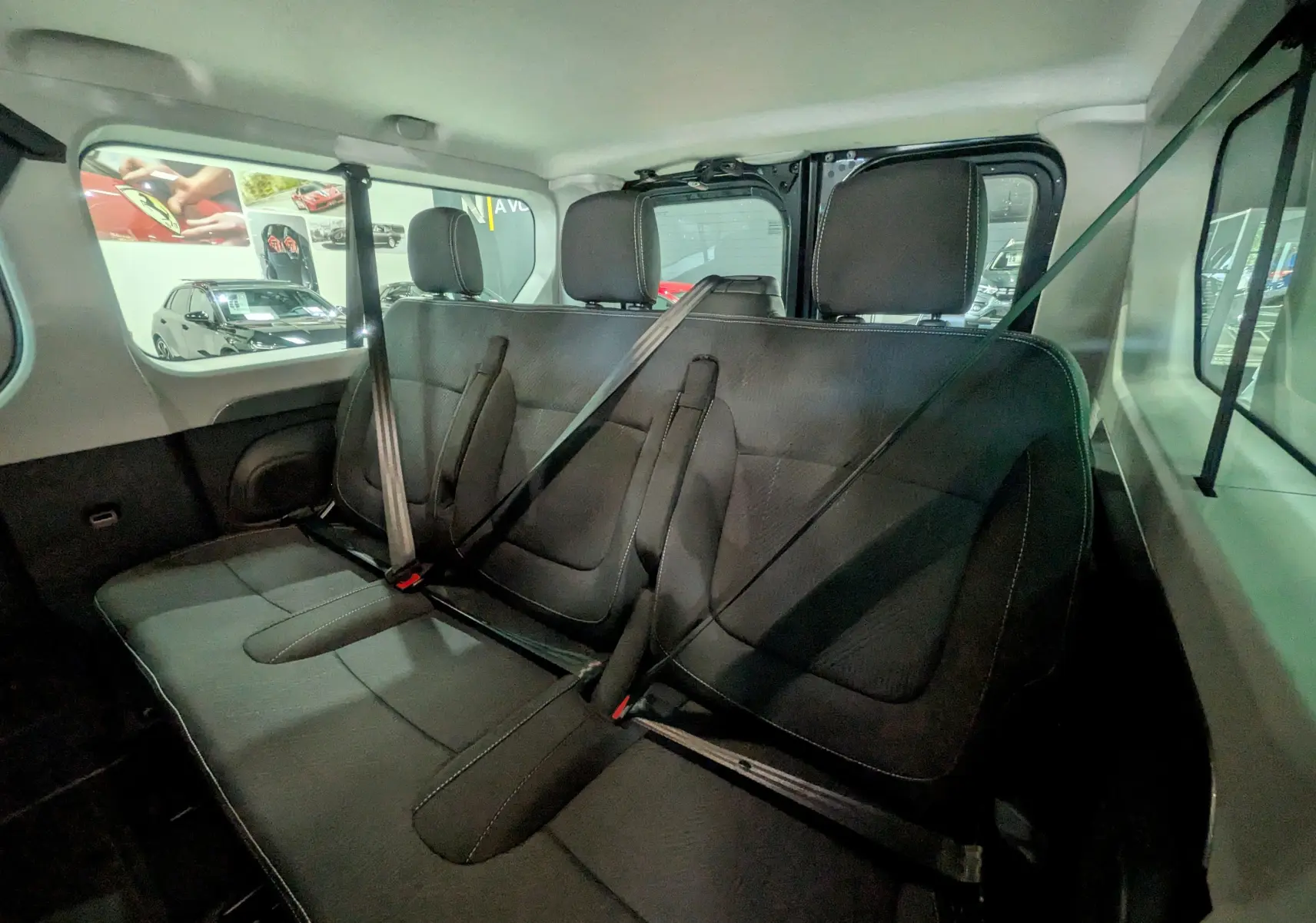 Vue intérieure arrière sur les sièges noirs du Renault Trafic Combi 2025, montrant les ceintures de sécurité et les appuie-têtes.
