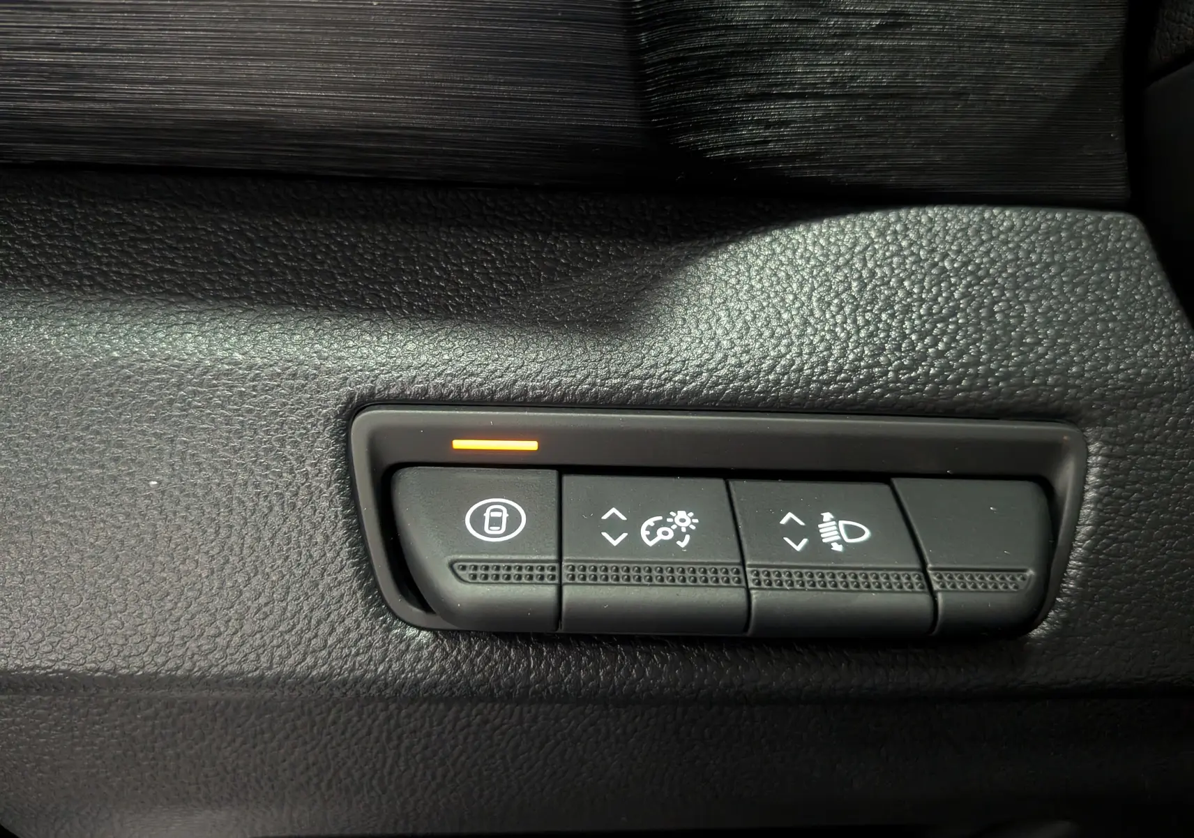 Gros plan sur les commandes de réglage des phares et du tableau de bord du Renault Trafic Combi gris Comète 2025.