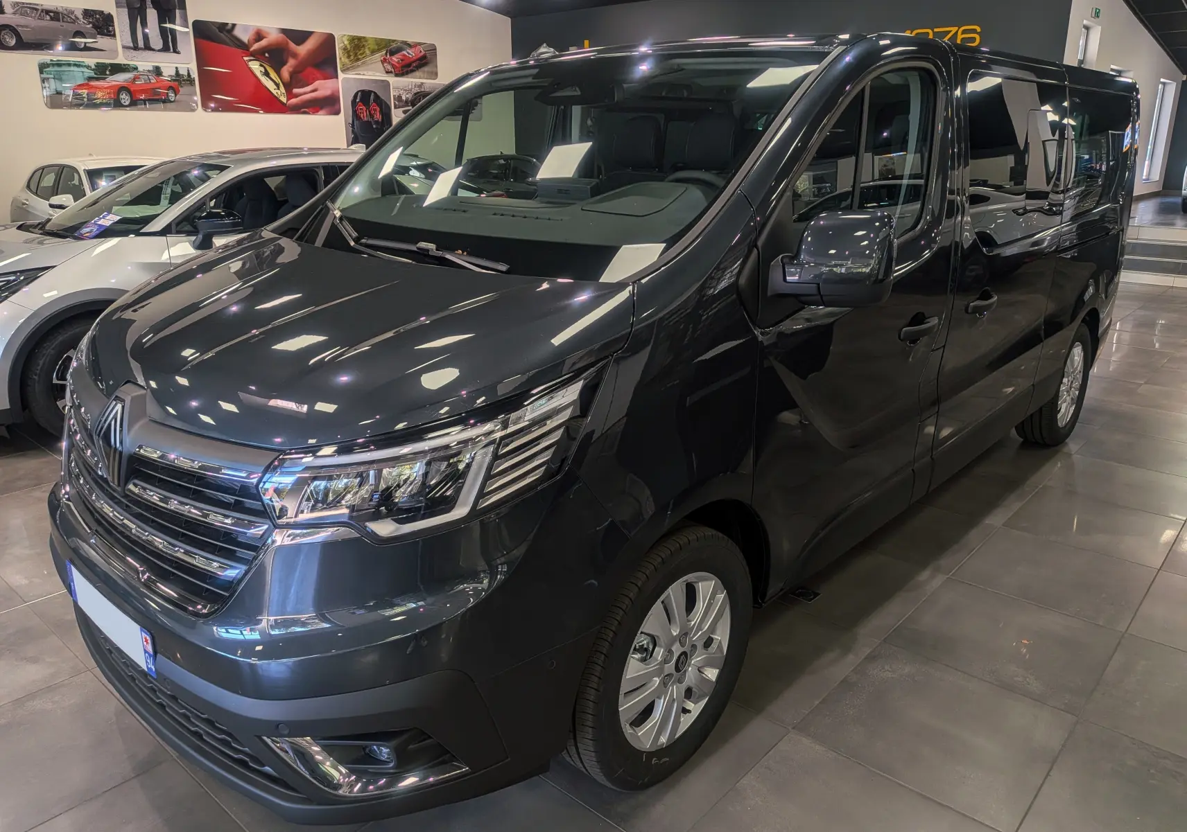 Renault Trafic Combi gris comète vu en 3/4 avant droit, mettant en valeur ses phares LED et sa calandre chromée.