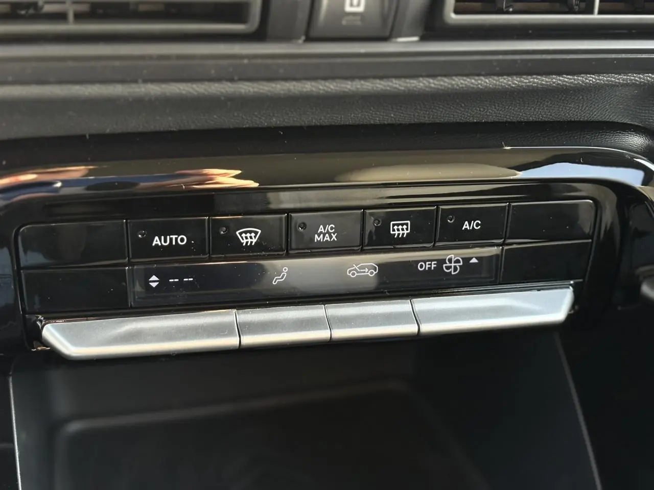 Gros plan sur les commandes de climatisation automatique en noir brillant dans le tableau de bord du Citroën C3 Aircross 2025.