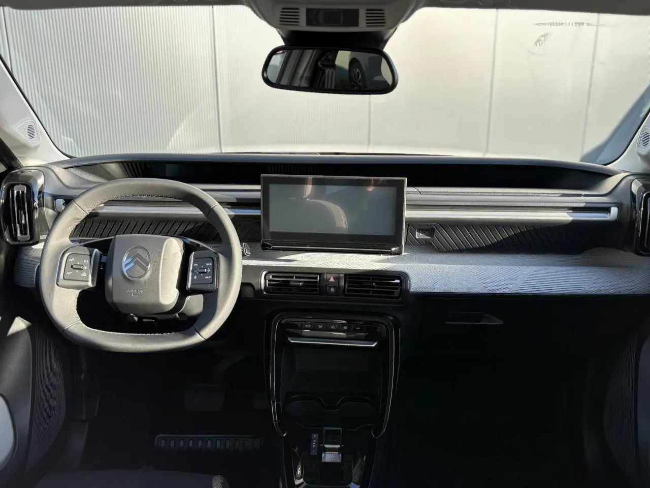 Vue intérieure avant du tableau de bord gris et noir du Citroën C3 Aircross Hybrid avec écran tactile central et volant multifonctions.