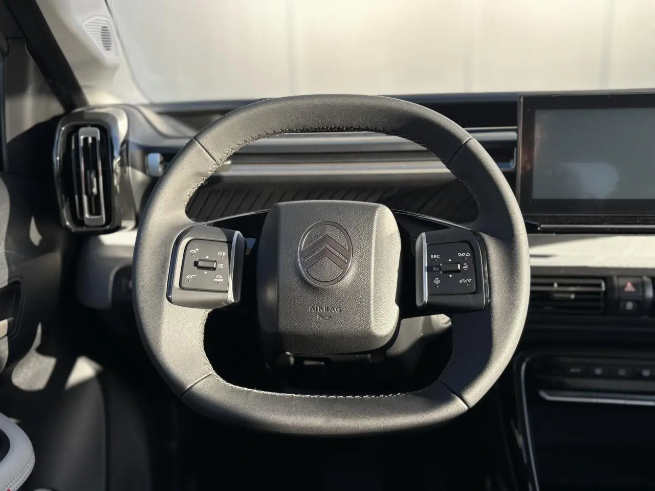 Vue rapprochée du volant noir de la Citroën C3 Aircross 2025 avec commandes multifonctions et tableau de bord gris.