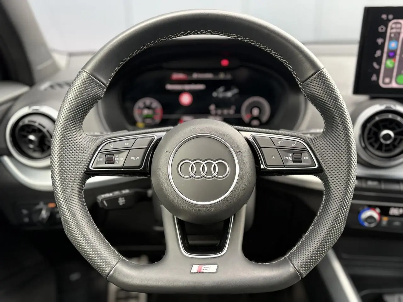 Volant multifonction en cuir noir avec logo Audi et badge S-Line, vue frontale centrée sur le volant.