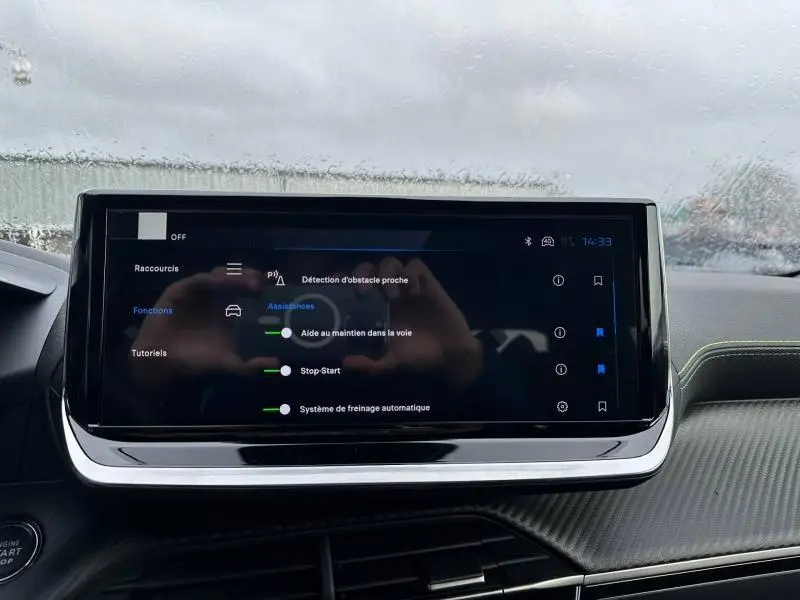 Écran tactile central du tableau de bord du Peugeot 2008 gris 2025, affichant les aides à la conduite.