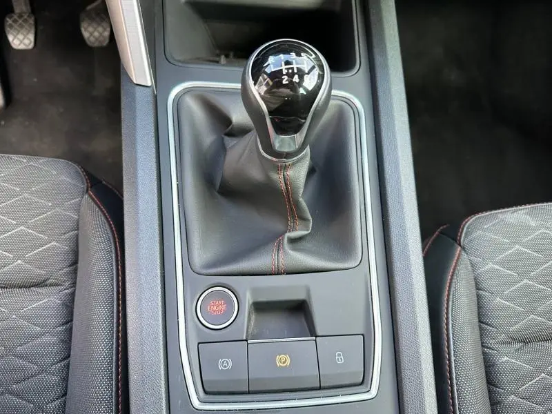 Gros plan sur la console centrale du SEAT LEON ST 1.5 eTSI Hybrid 2025 avec levier de vitesse manuel et bouton start/stop.