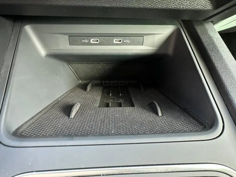Vue rapprochée de la zone de rangement avant avec deux ports USB-C dans le SEAT LEON ST 1.5 eTSI Hybrid 2025 noir métallisé.