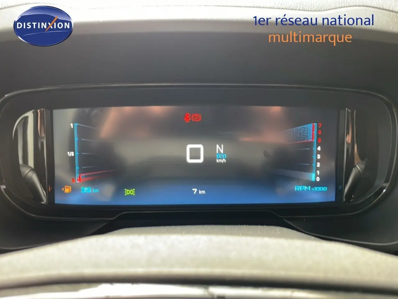 Tableau de bord numérique du Citroën Berlingo gris, affichant la vitesse, la consommation et le régime moteur, vu de face.