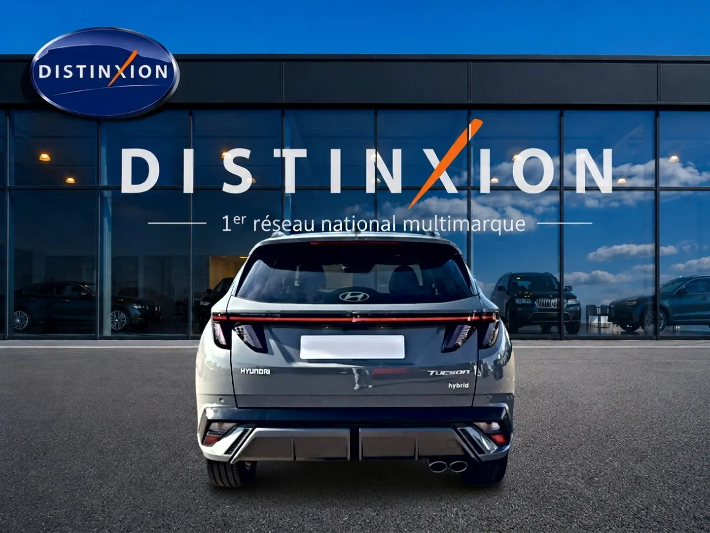 Vue arrière d'un Hyundai Tucson gris shadow hybride, avec feux arrière LED et double sortie d'échappement visible.