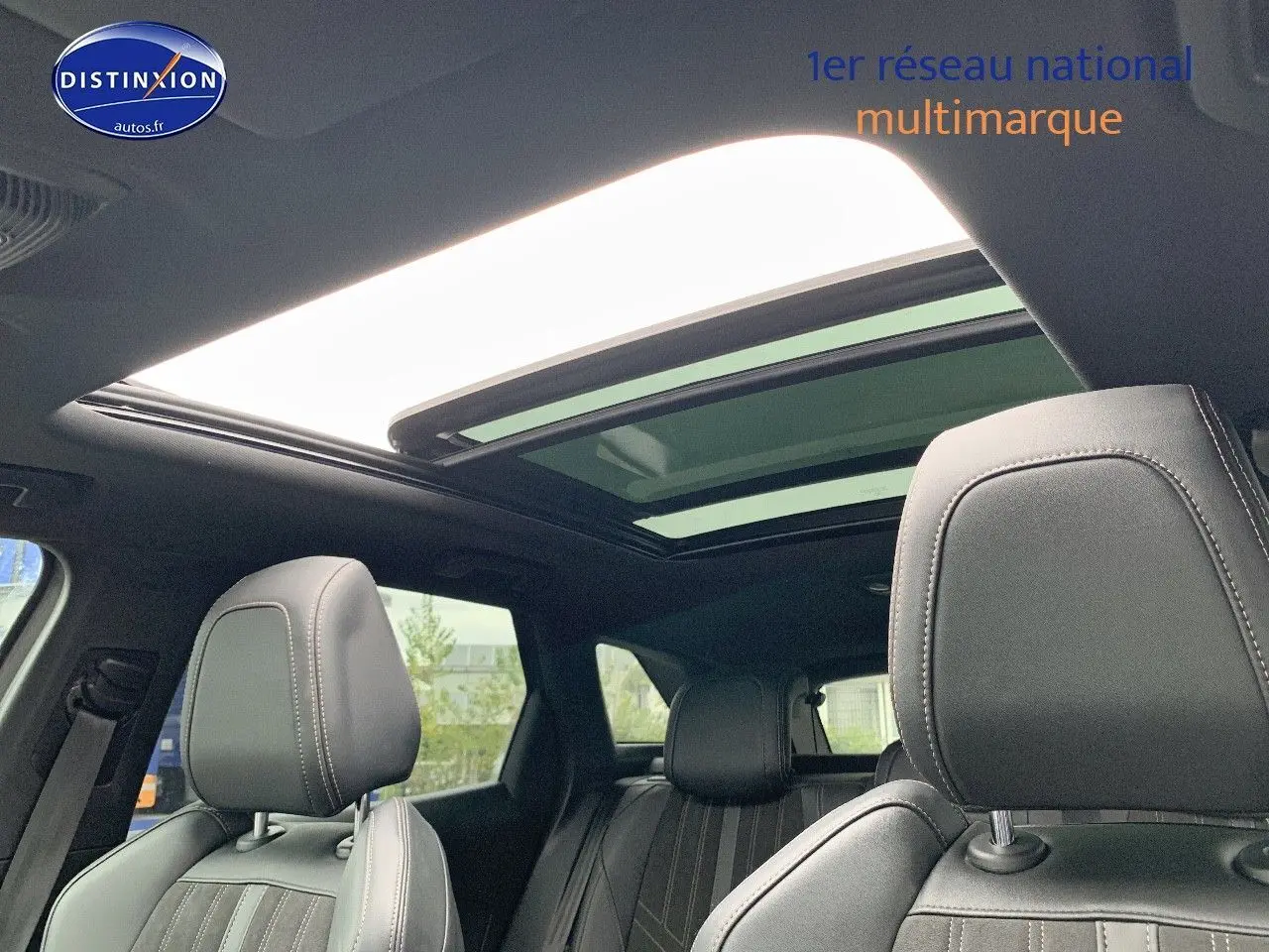 Vue intérieure du Peugeot 3008 gris platinium, montrant les sièges avant en cuir noir et le toit panoramique ouvert.