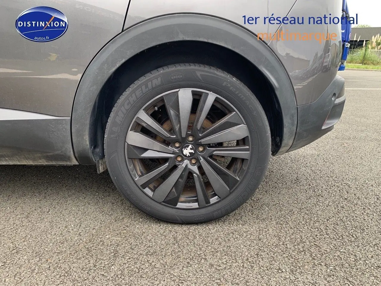 Gros plan sur la roue arrière droite du Peugeot 3008 gris platinium métal avec jante alliage sombre et logo lion central.