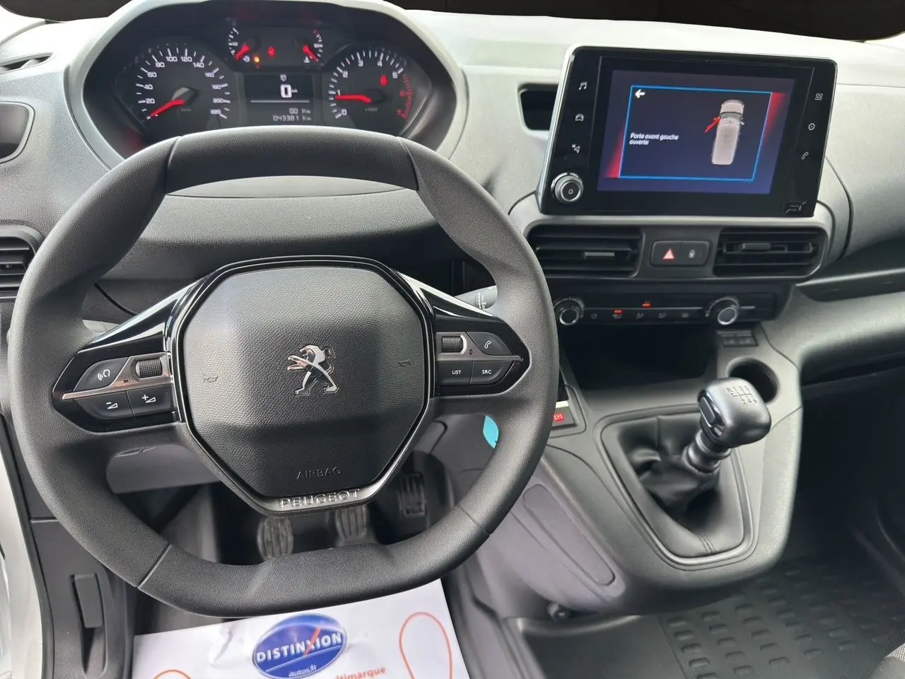 Vue intérieure du tableau de bord du Peugeot Partner 2022 avec volant multifonction et écran tactile central affichant une alerte.