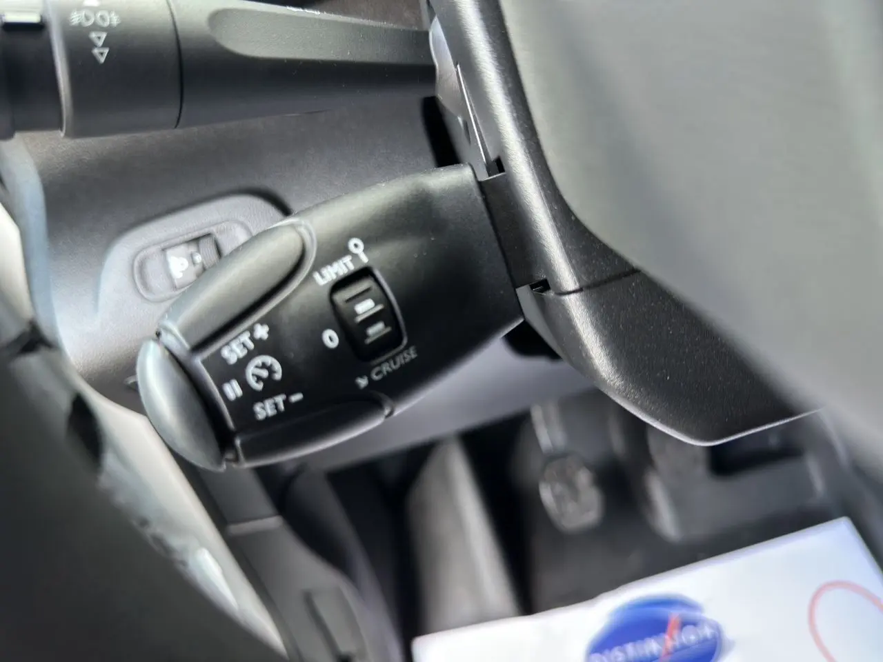 Gros plan sur la commande de régulateur de vitesse noire dans l'habitacle du Peugeot Partner blanc 2022.