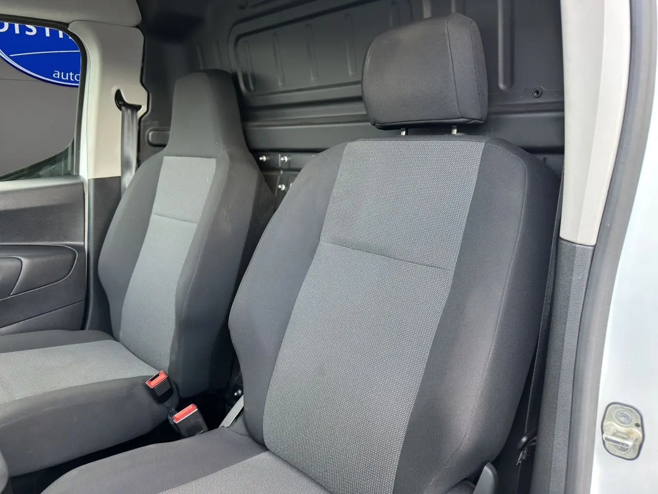 Vue intérieure rapprochée des sièges avant gris foncé et clair du Peugeot Partner blanc 2022, version 1000KG BlueHDi 100 Premium.