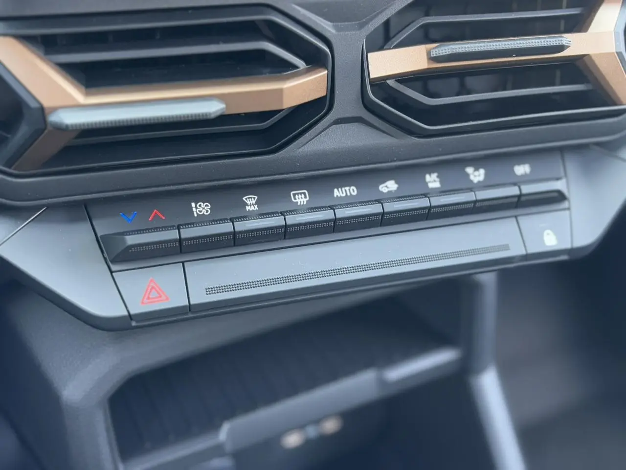 Gros plan sur la console centrale du Dacia Duster 2025 noir nacré, mettant en valeur les commandes de climatisation et les aérateurs.