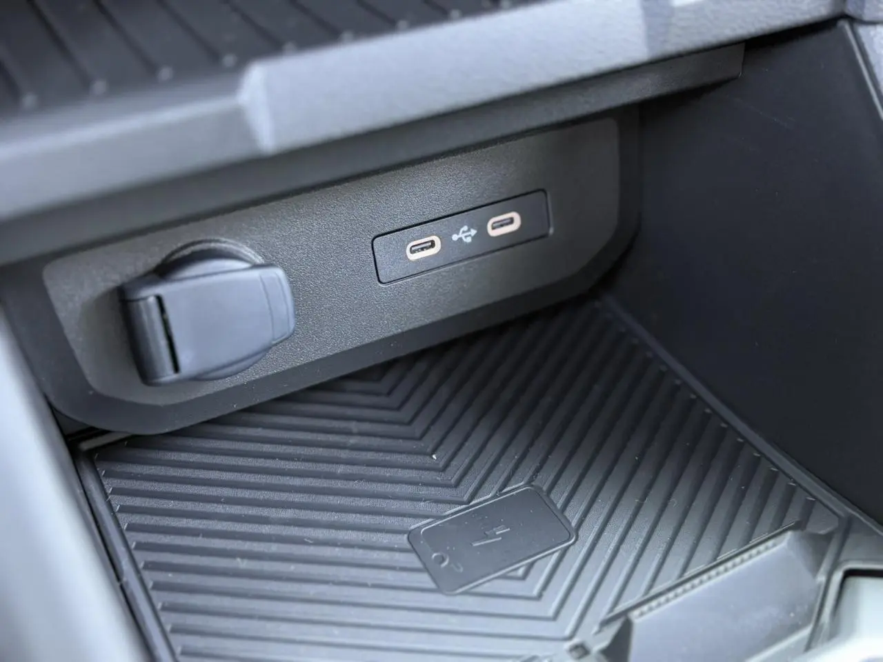 Gros plan sur la console centrale du Dacia Duster 2025, montrant les ports USB-C et le chargeur à induction noir.