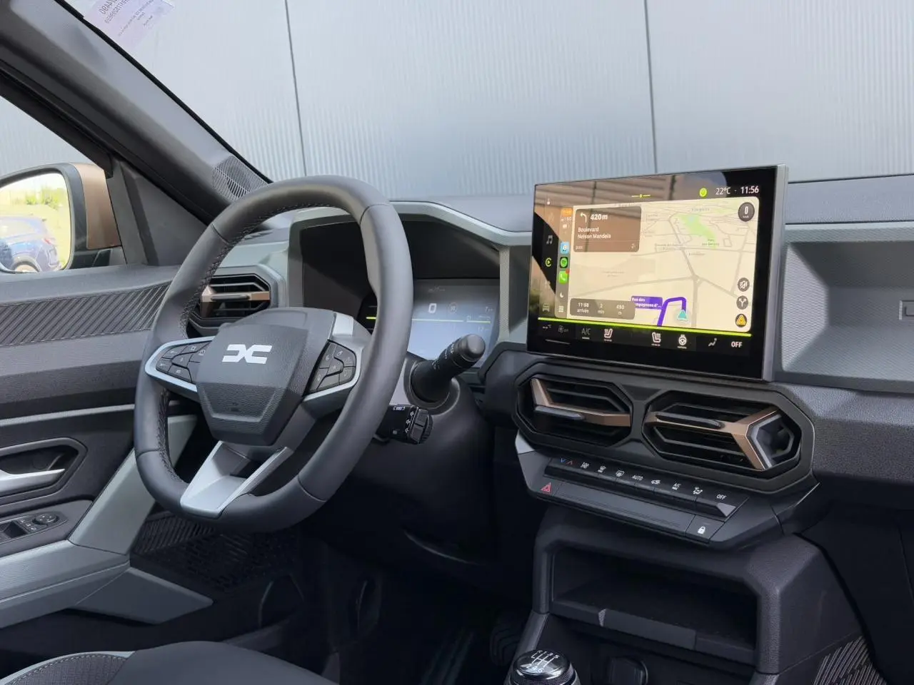 Intérieur du Dacia Duster 2025, vue côté conducteur sur volant, écran tactile GPS et aérateurs hexagonaux.