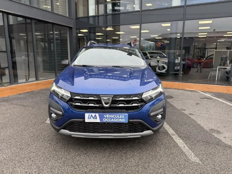 Vue avant d'une Dacia Sandero Stepway 1.0 ECO G 100 Essential bleu métal avec calandre noire et plaques de protection grises.