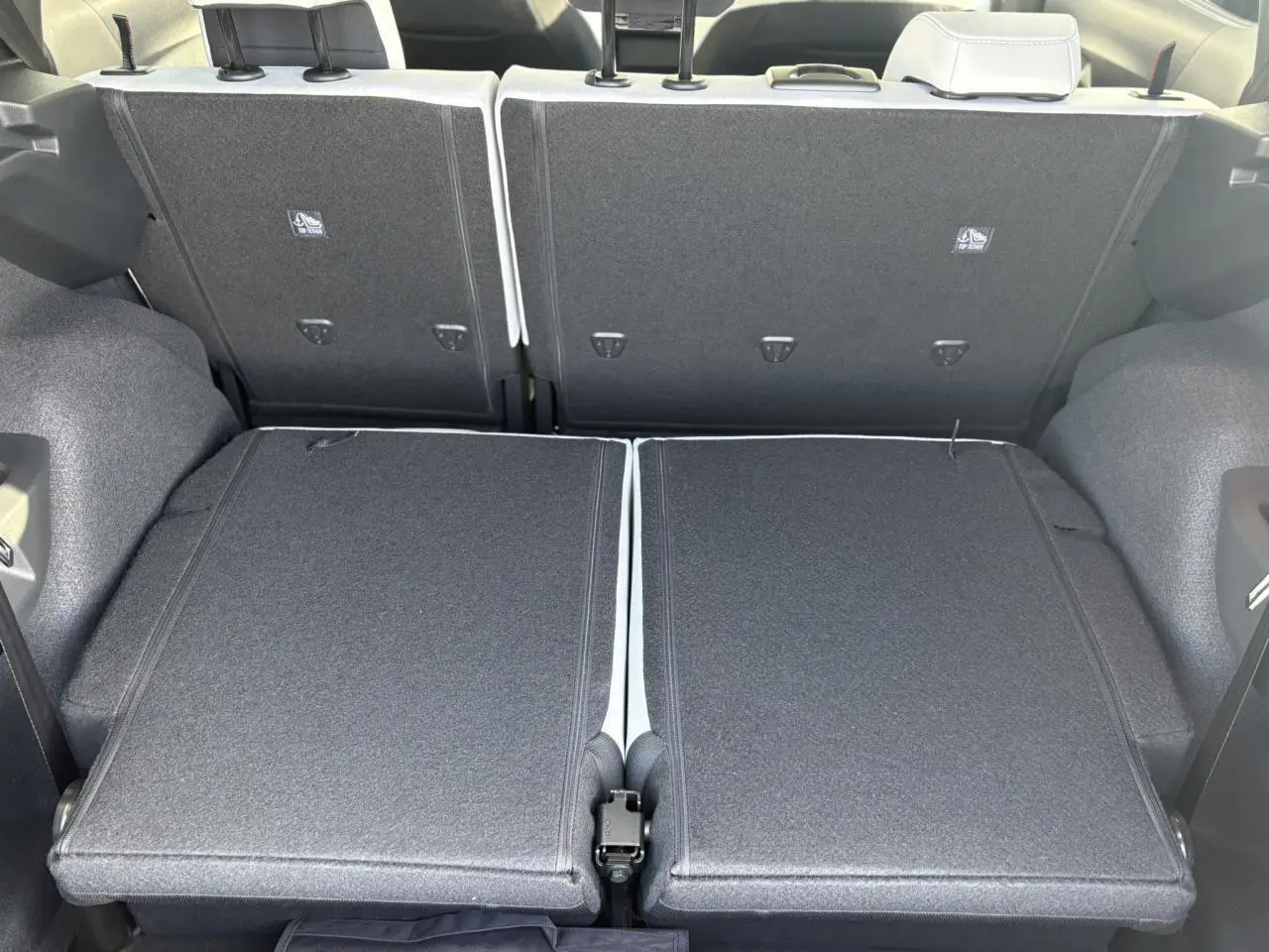 Vue arrière du coffre du Citroën C3 Aircross 2025 avec banquette 3e rang rabattue, intérieur gris foncé et tissu texturé.