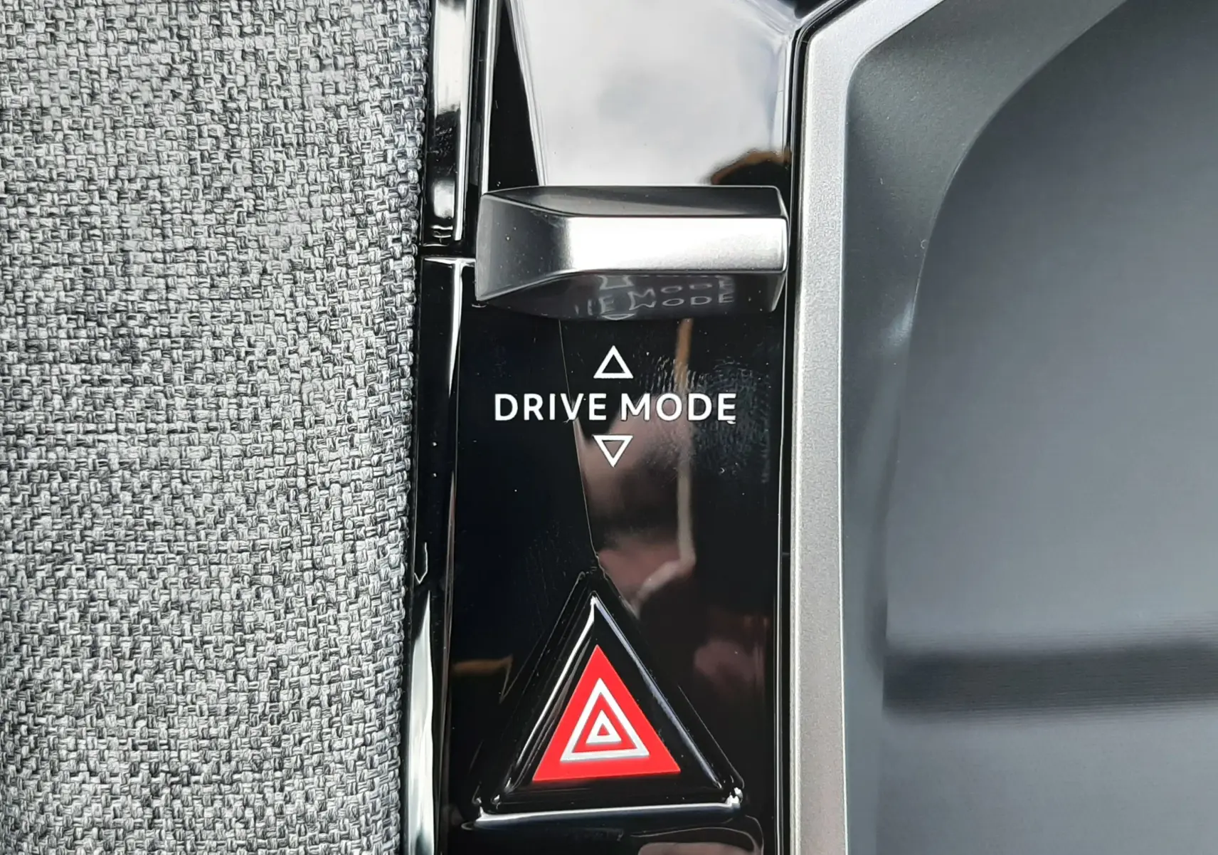 Gros plan sur le bouton Drive Mode et le triangle de signalisation rouge sur la console noire intérieure du Peugeot 3008 gris titane.