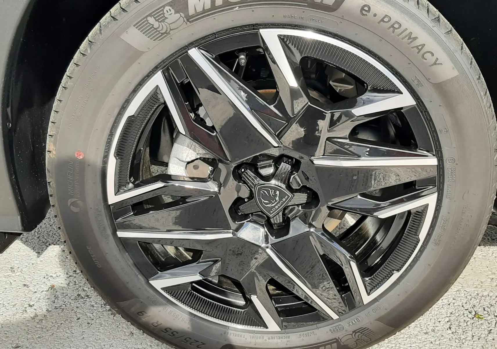 Gros plan sur la roue avant gauche du Peugeot 3008 gris titane, jante alliage noire et pneus Michelin e-Primacy.