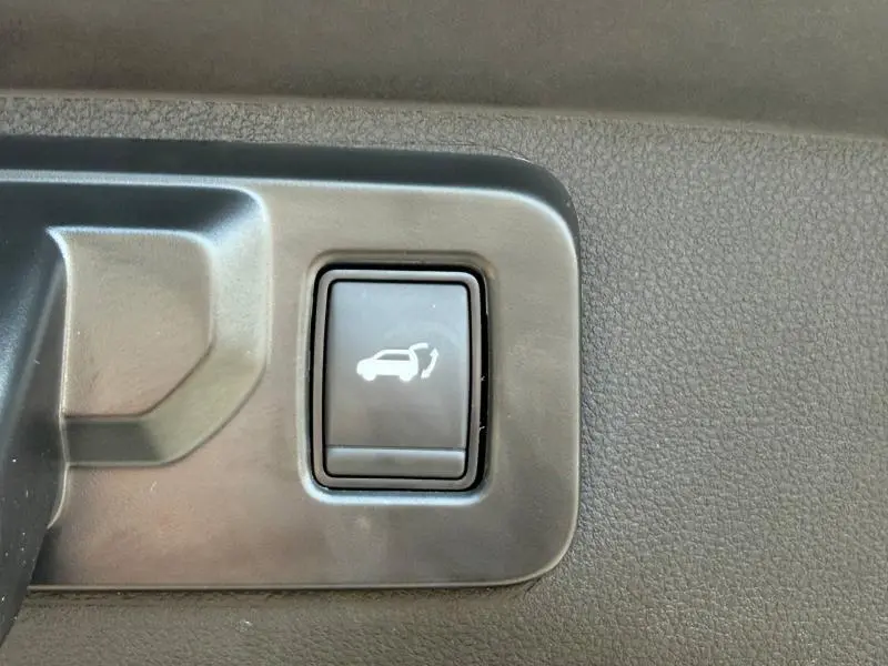 Gros plan sur le bouton d'ouverture électrique du coffre dans l'habitacle du Renault Rafale noir étoilé.