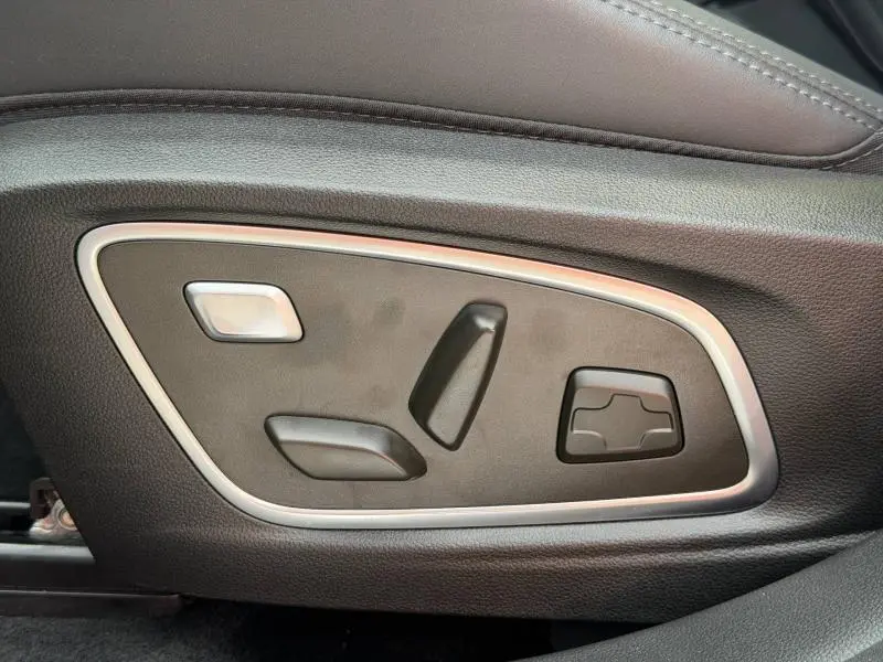 Gros plan sur les commandes de réglage électrique du siège côté gauche en cuir noir du Renault Rafale 2025.