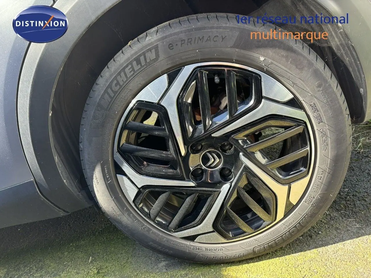 Gros plan sur la jante noire et argentée d'une Citroën C4 gris Artense, mettant en valeur le logo Citroën central.